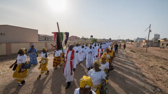 Rev. David Bitrus of the LCCN carries the banner as the procession moves into Covenant Ground on Sunday. 