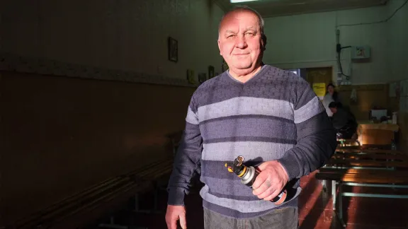 Sergii Shyshko, volunteer and community member, cuts the wood and prepares the stove at the heating point in Shyshkovaska: “When I'm at home I'm alone, but here I have more fun and don't feel so alone." Photo: LWF/ L. Gillabert